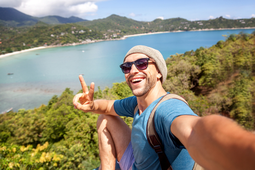 Traveler taking a selfie on a hilltop above a tropical bay