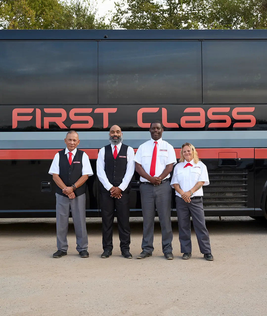 Four First Class Transportation drivers in uniform standing in front of a motorcoach