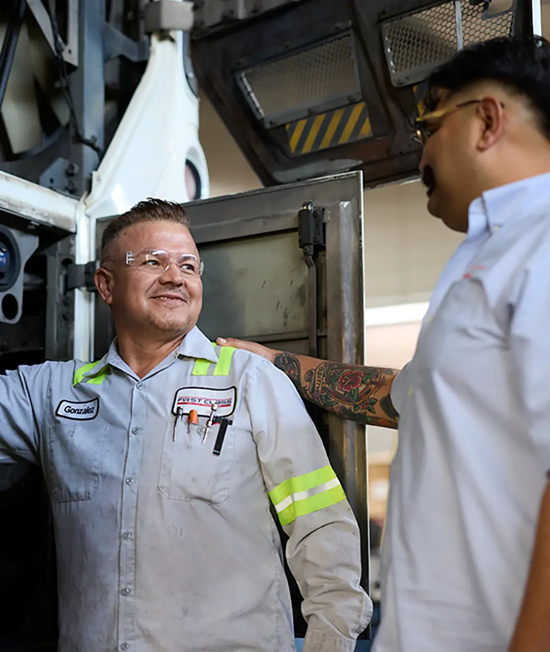 Two First Class Transportation mechanics talking in the maintenance bay