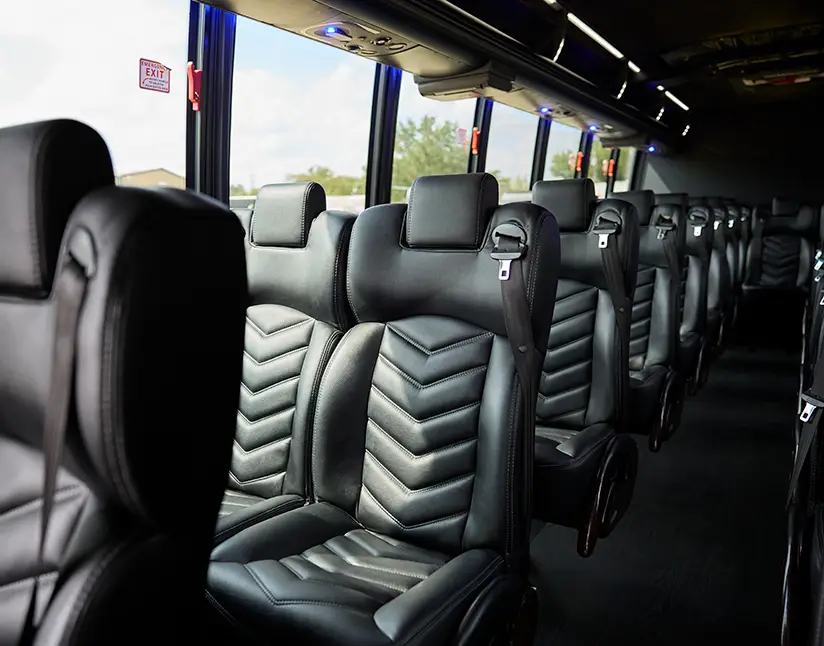 Row of black leather reclining seats with seatbelts inside a First Class Transportation motorcoach