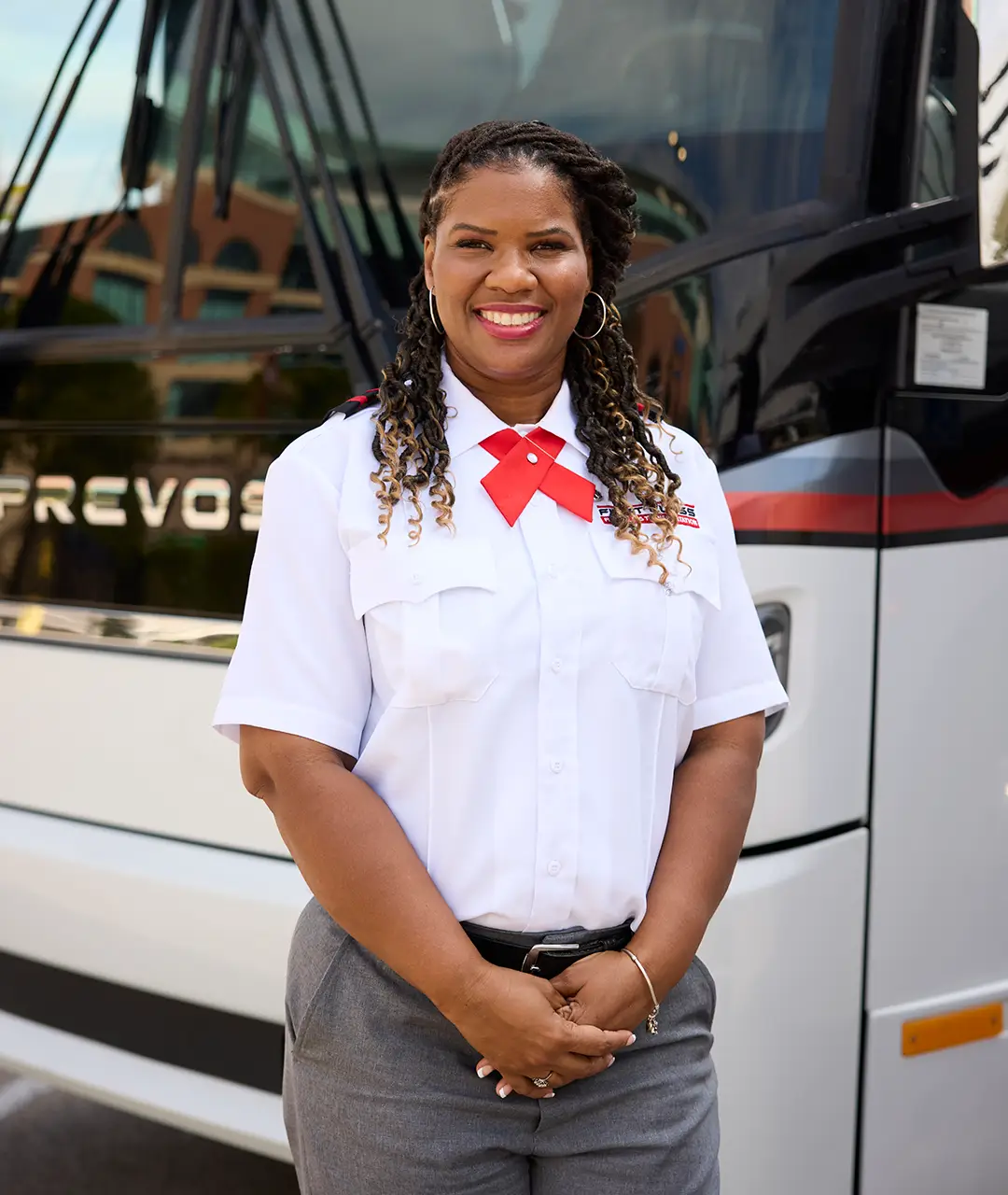 First Class Transportation driver in uniform standing in front of a white First Class motorcoach