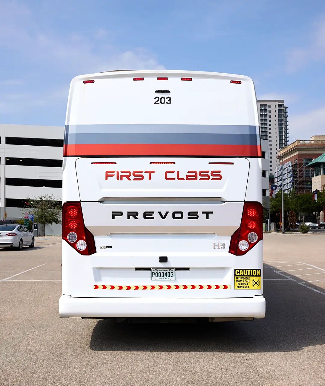 Rear view of a white First Class Transportation Prevost motorcoach with red First Class lettering