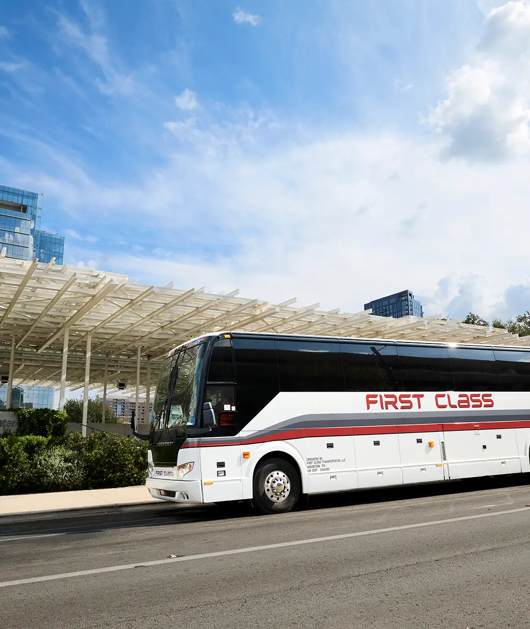 White First Class Transportation Prevost motorcoach parked on a downtown street
