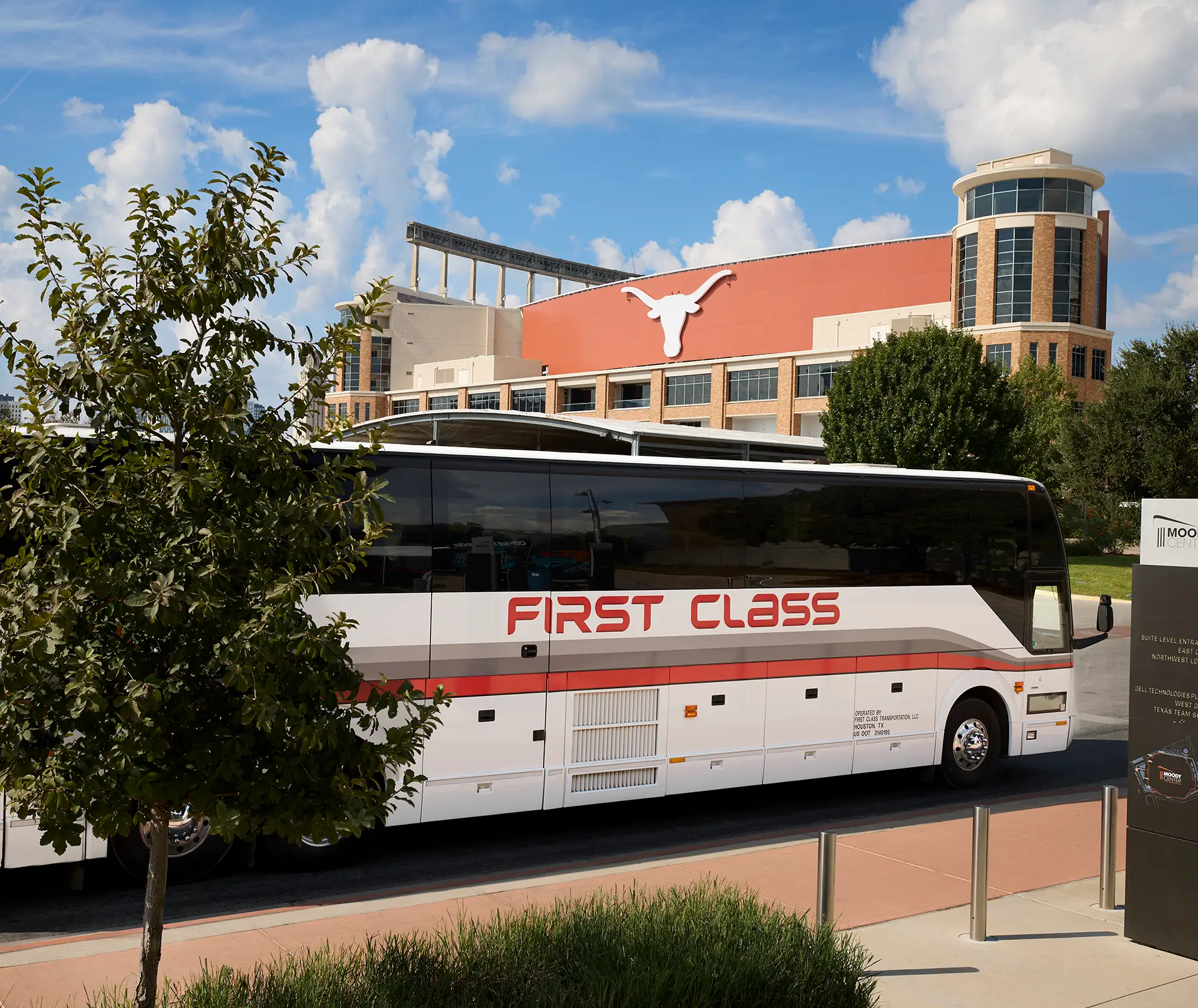 White First Class Transportation motorcoach parked outside the Moody Center in Austin, Texas