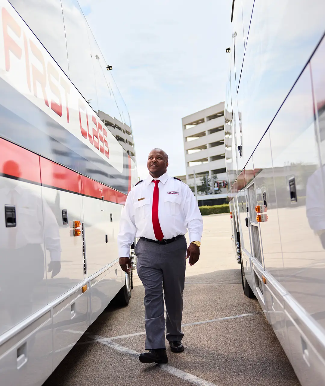 First Class Transportation driver in uniform walking between two motorcoaches