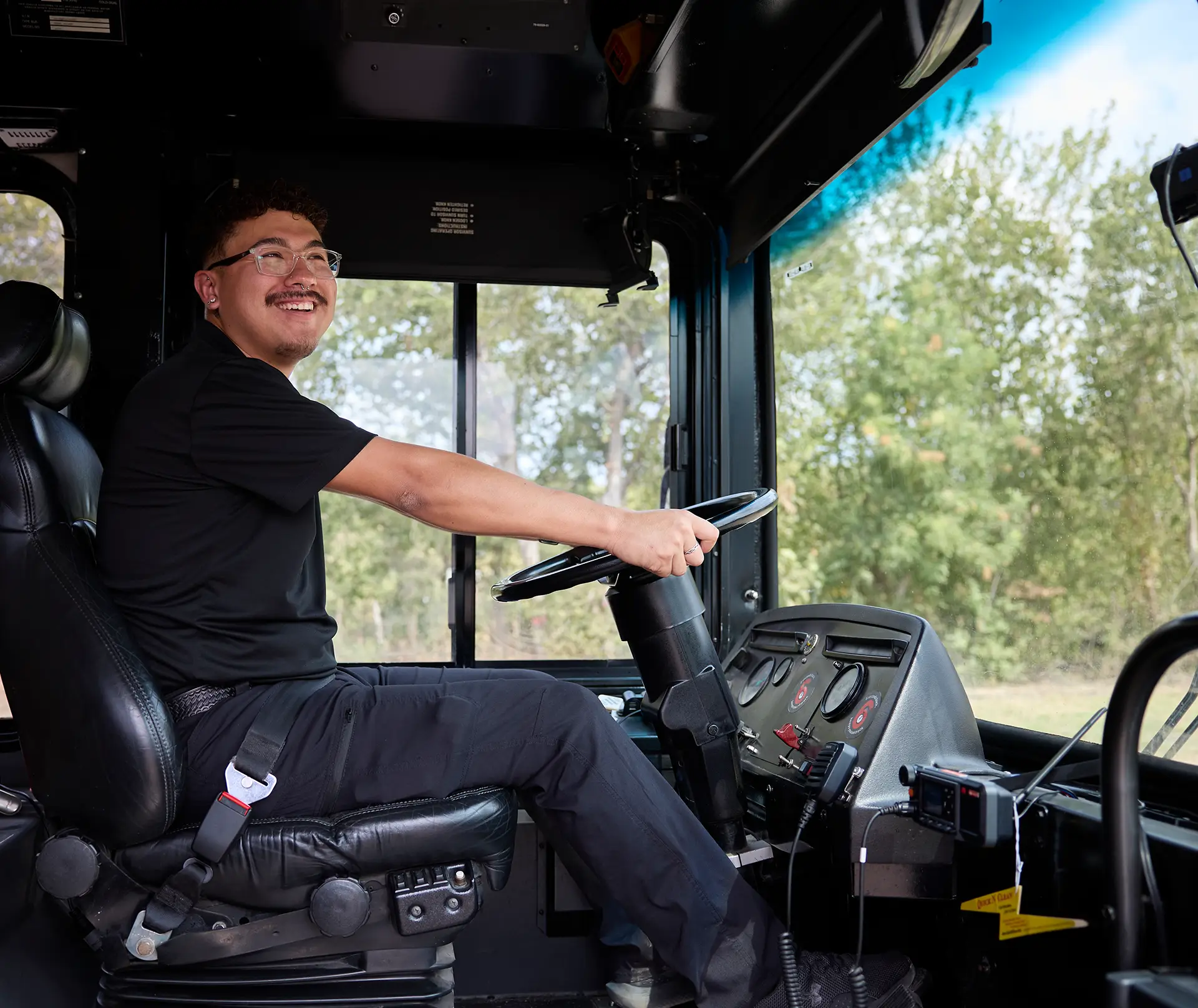 Smiling First Class Transportation driver seated at the wheel of a bus