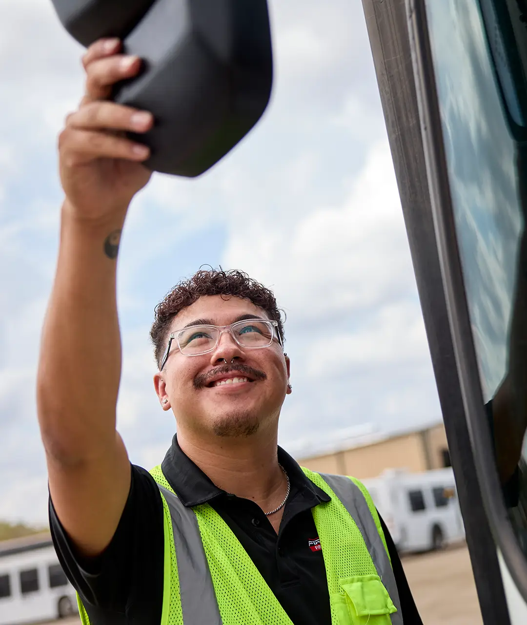 First Class Transportation technician in a safety vest adjusting the mirror of a bus