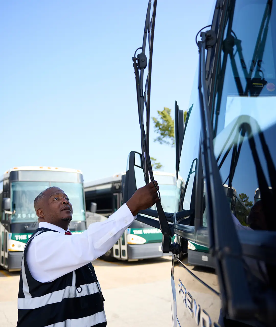 First Class Transportation driver performing a pre-trip windshield wiper check on a motorcoach