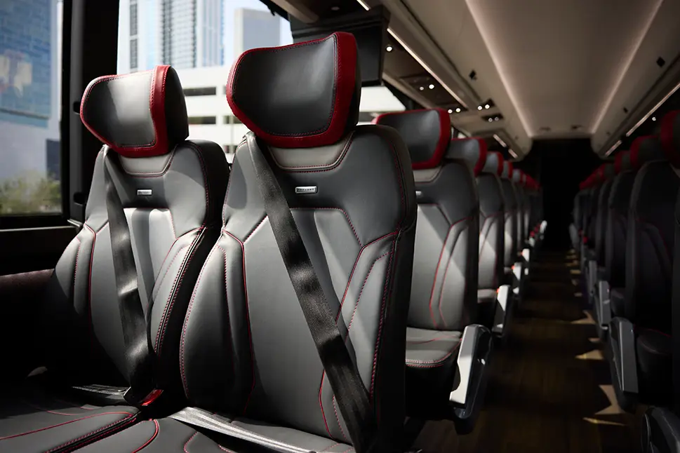 Interior of a First Class Transportation motorcoach with black leather reclining seats and red stitching