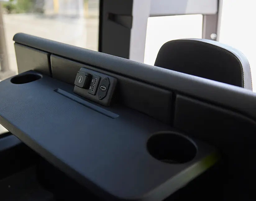 Motorcoach seatback tray table with power and USB outlets and a cupholder
