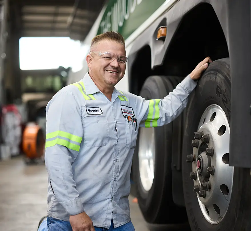 First Class Transportation technician standing beside a motorcoach wheel in the maintenance shop