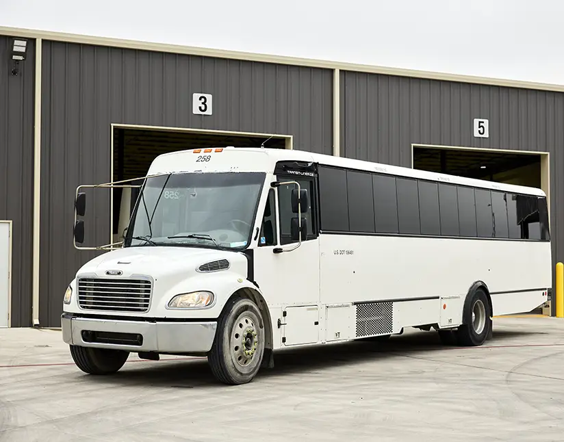 White First Class Transportation commercial bus parked outside a maintenance facility