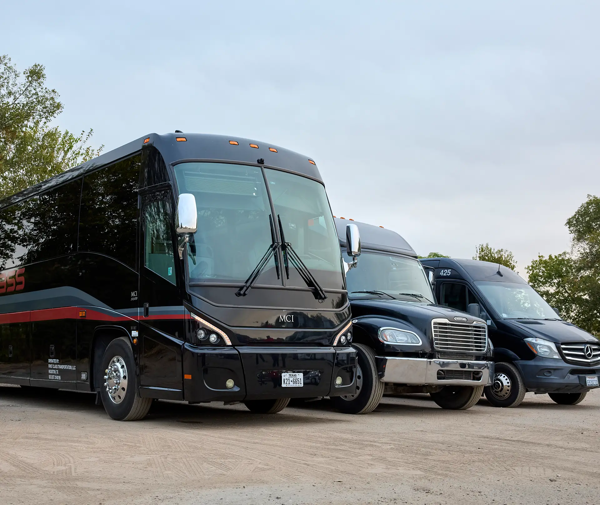 Black First Class Transportation motorcoach, minibus, and Sprinter van parked in a row