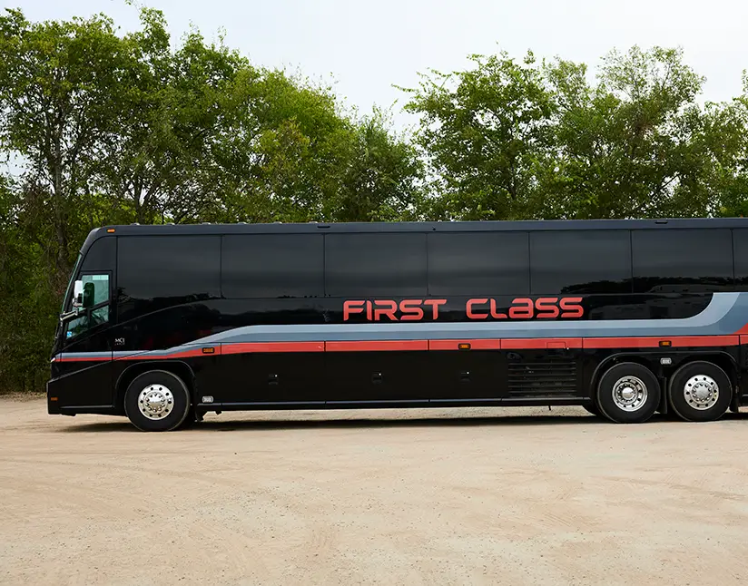 Black First Class Transportation mid-size motorcoach parked on gravel