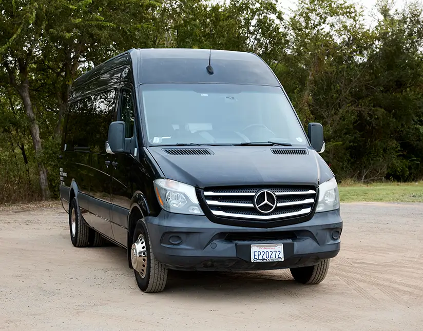 Black First Class Transportation Sprinter van parked on gravel