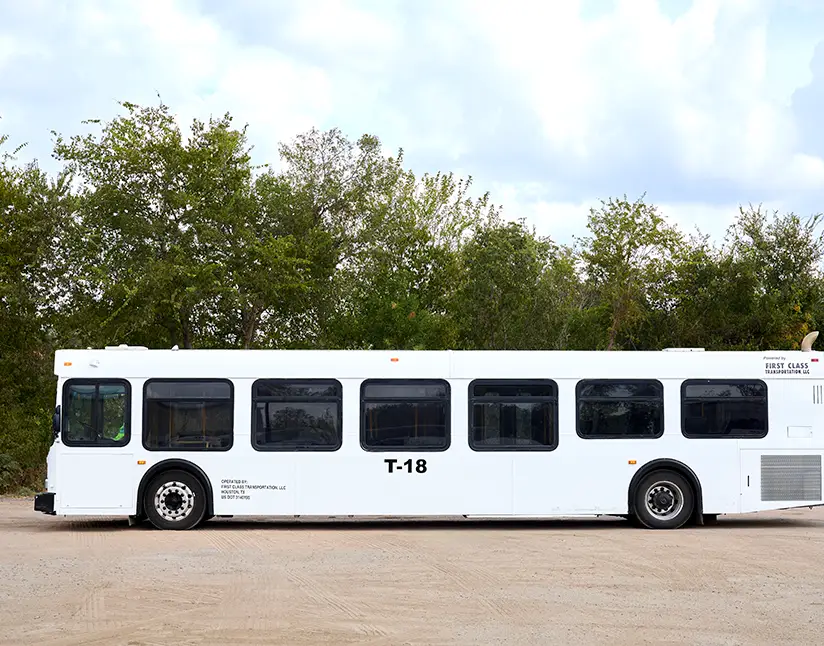 White First Class Transportation transit bus parked on gravel