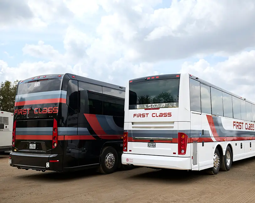 Black and white First Class Transportation motorcoaches parked side by side