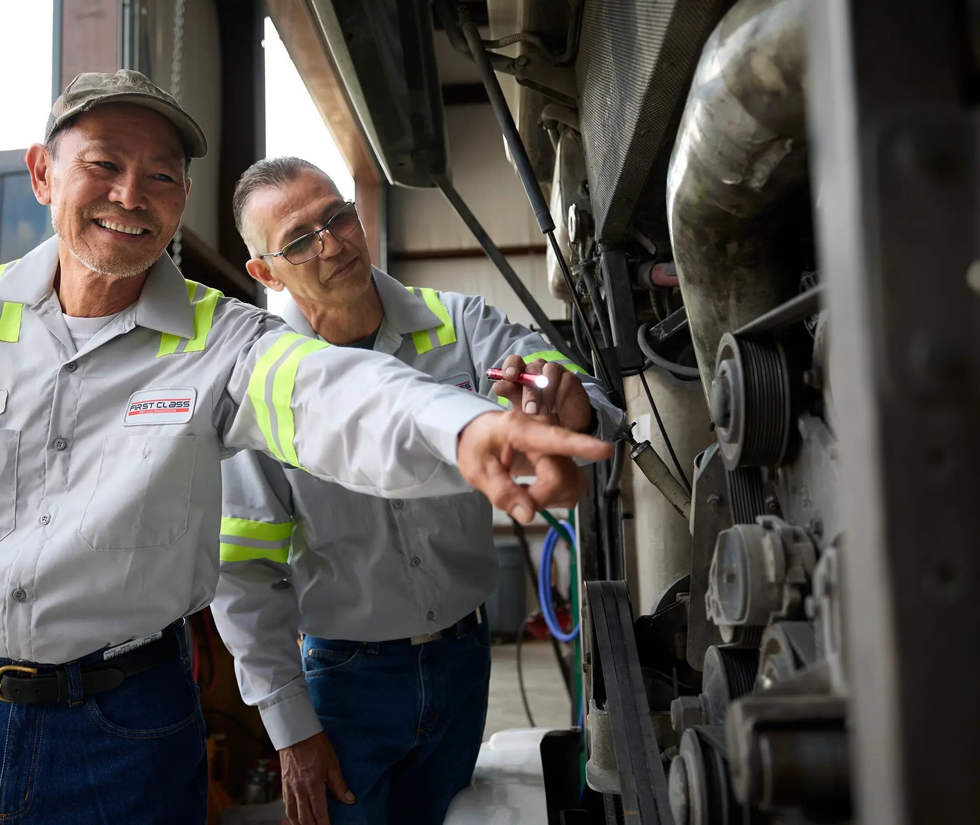 Two First Class Transportation technicians inspecting a motorcoach engine during maintenance