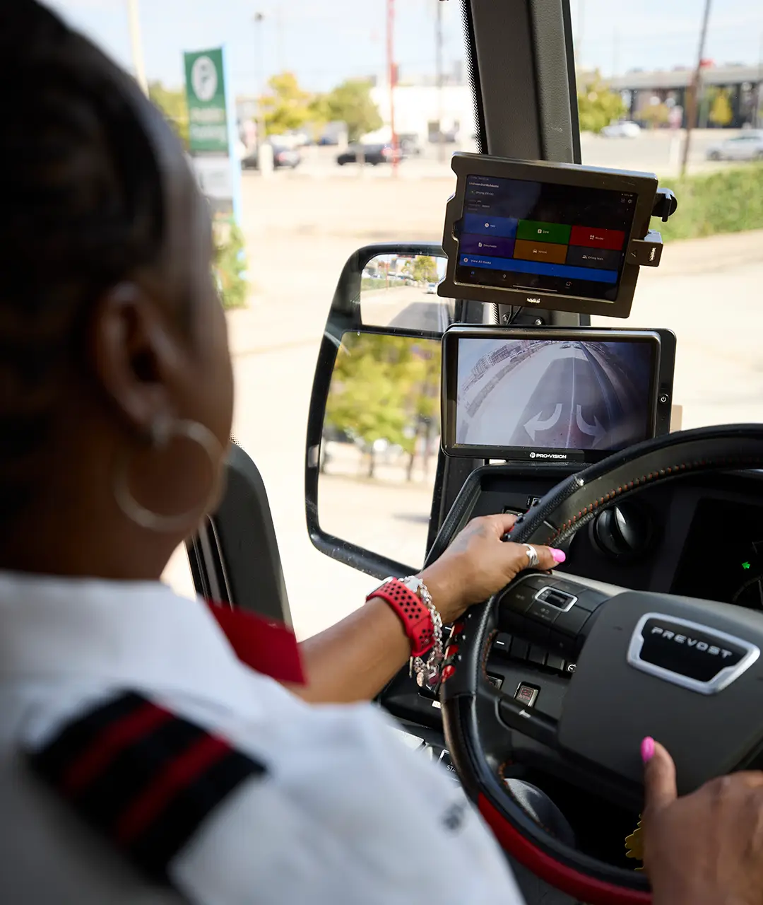First Class Transportation driver at the wheel of a Prevost motorcoach with dashboard tablet and backup camera displays