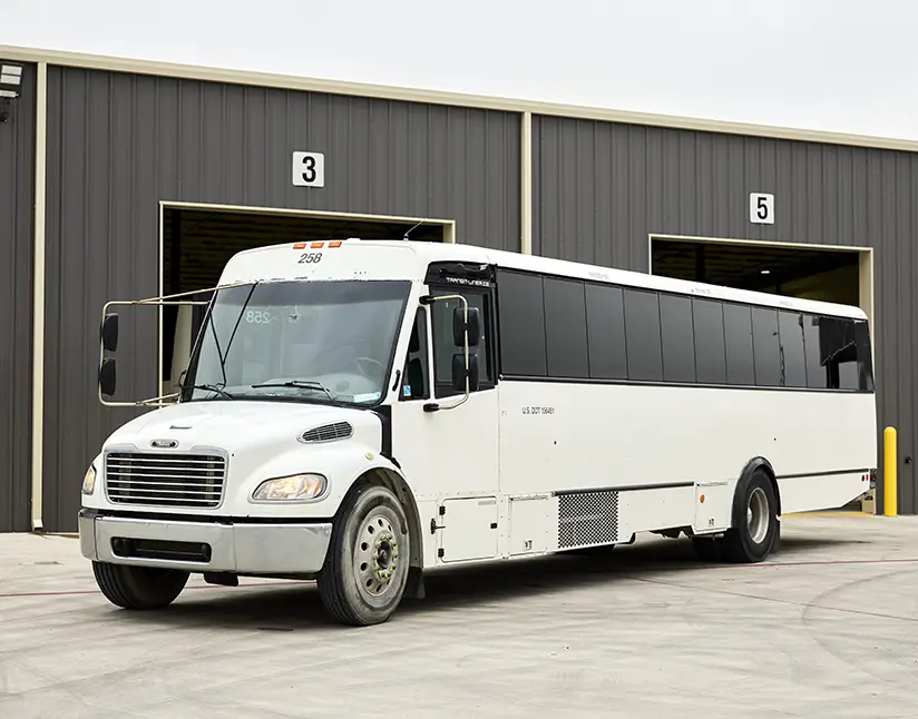 White First Class Transportation commercial bus parked outside the maintenance bays