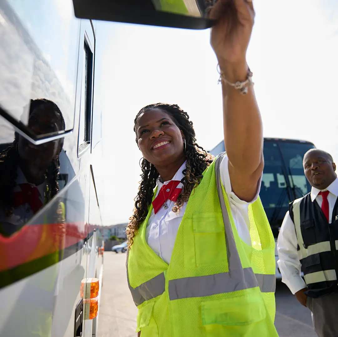 First Class Transportation driver doing a pre-trip mirror check beside a motorcoach
